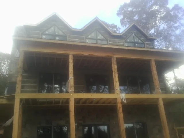 Dormers and porch framing on a large log home under construction — Roof Coating work by our crew in Braddock