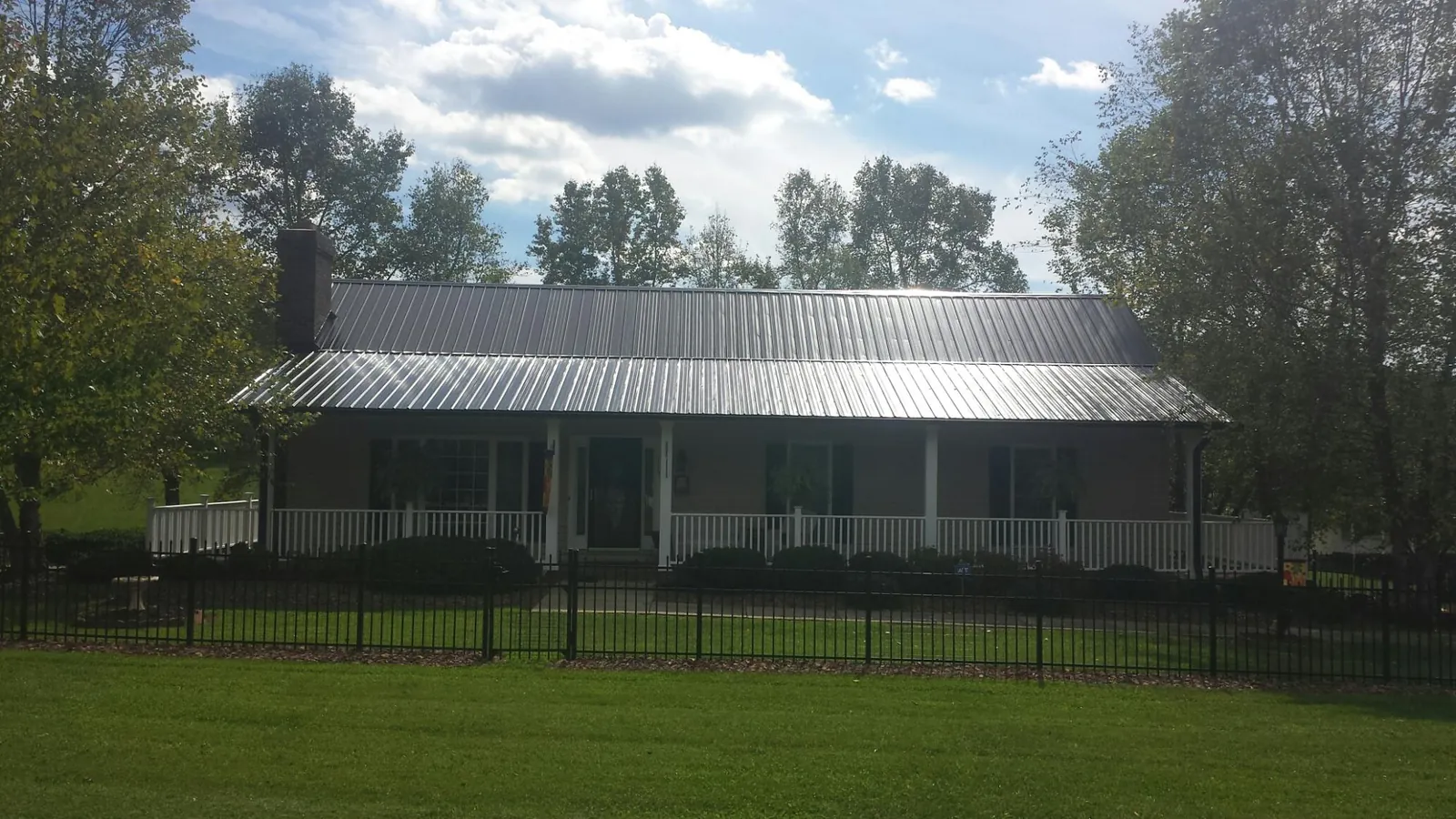 Gray metal roof on a brick ranch with a full width front porch — Gutter Guard Installation work by our crew in Braddock