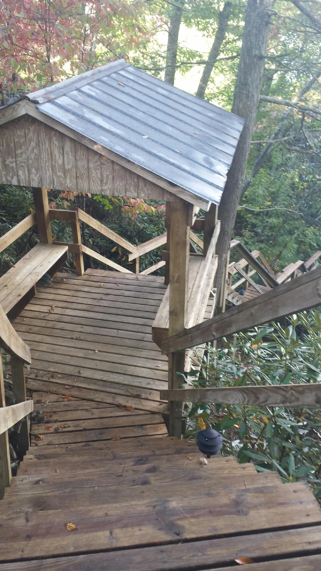 Metal roofed shelter over wooden steps on a wooded walkway — Skylight Repair & Installation work by our crew in Braddock